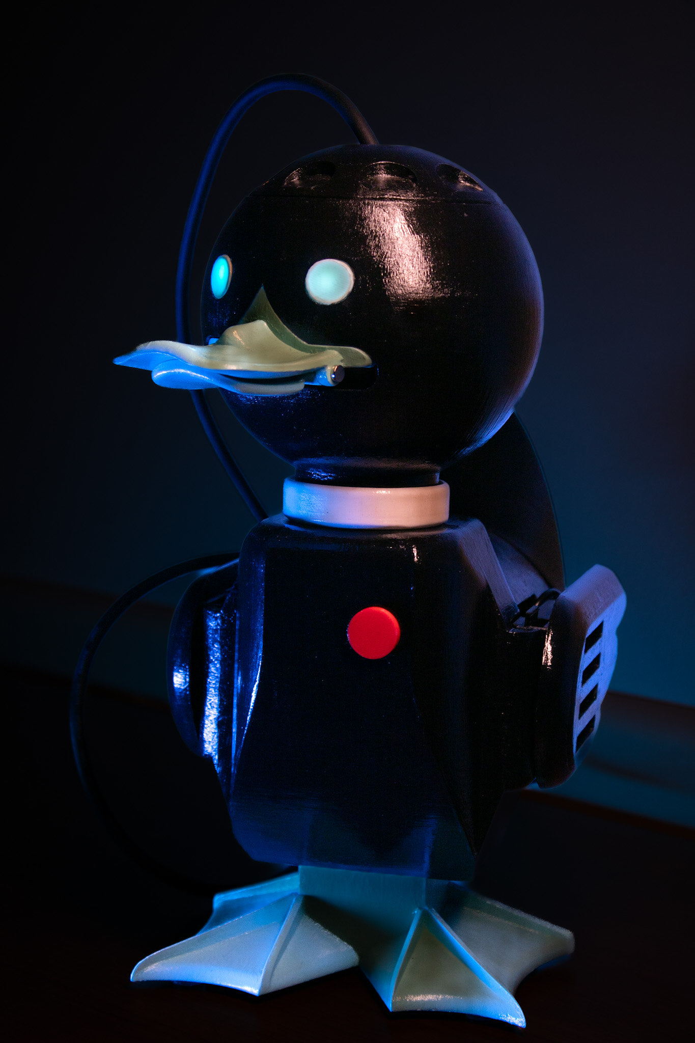 A black duck-shaped device is standing in a dark room