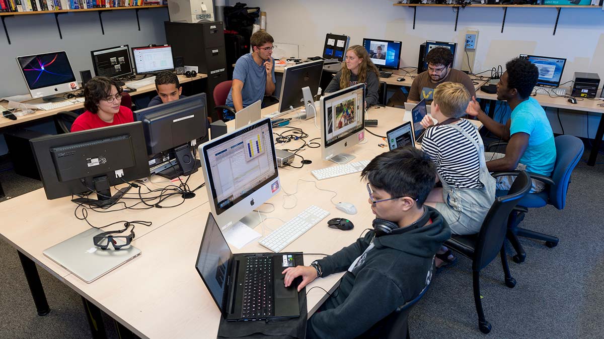 8 students sitting around a table working on computers.