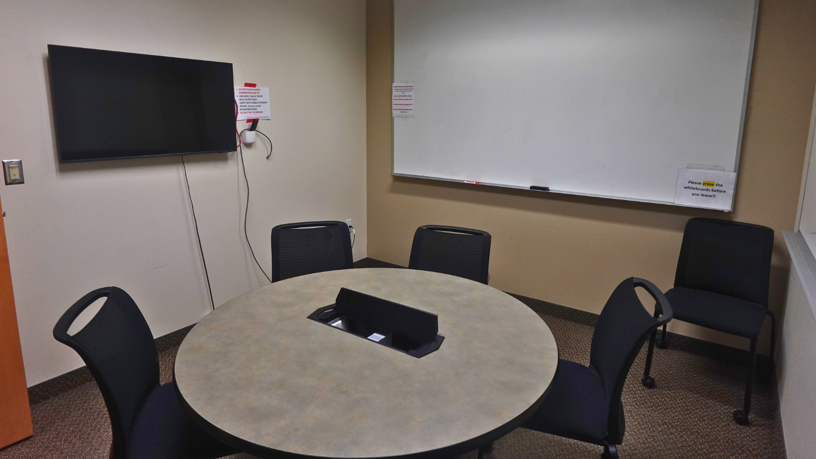 small room with a tv on one wall and white boards on the other walls