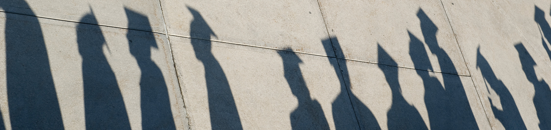 Shadows of students in graduation clothing.