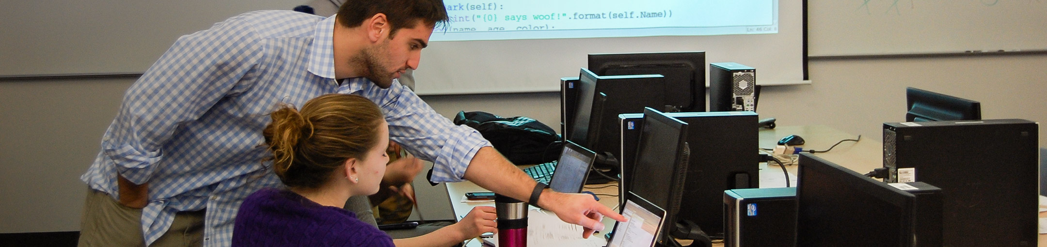 Person helping a student on a computer.