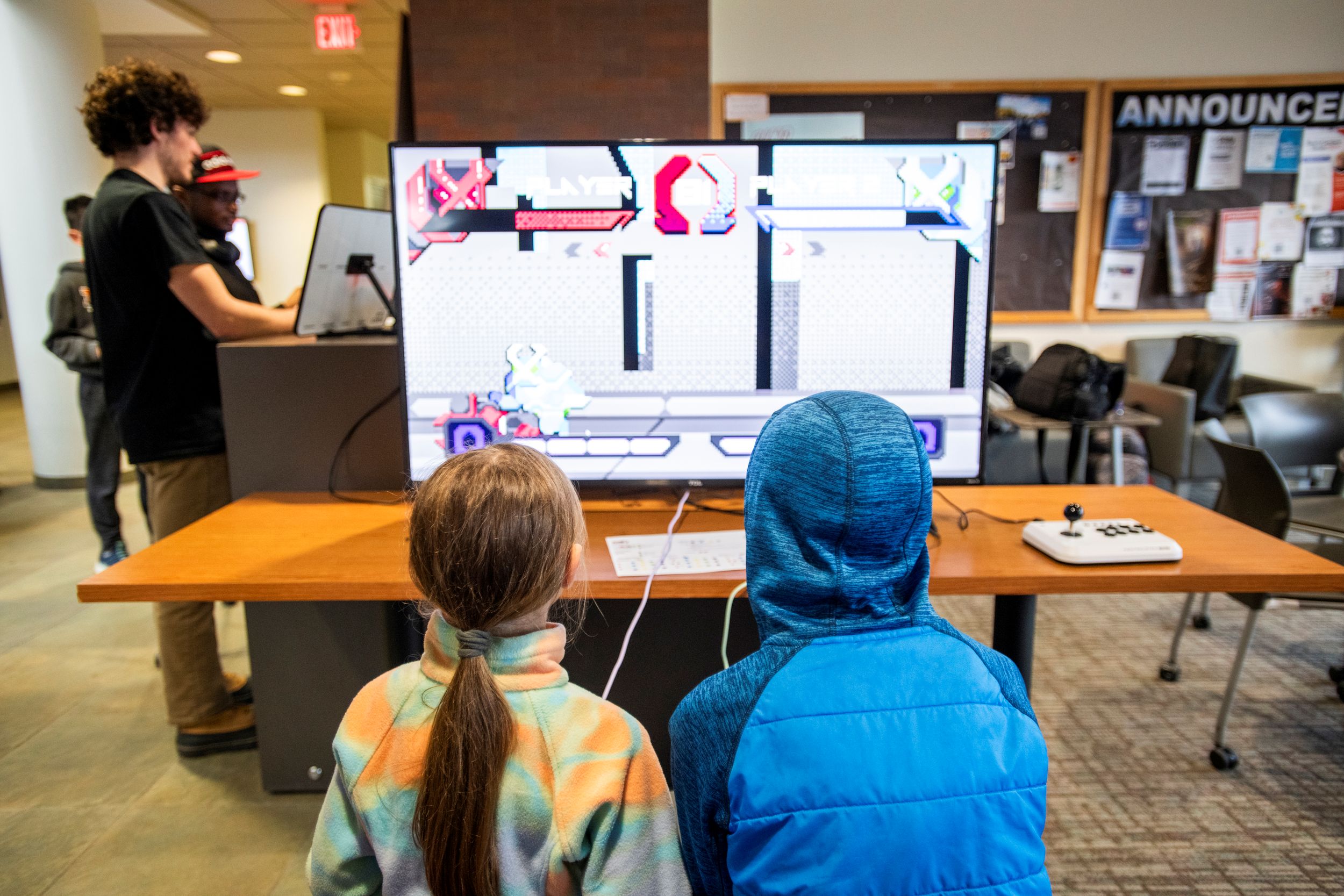 Two people in front of a computer monitor playing Ninjas on Trampolines, a game developed by RIT students.