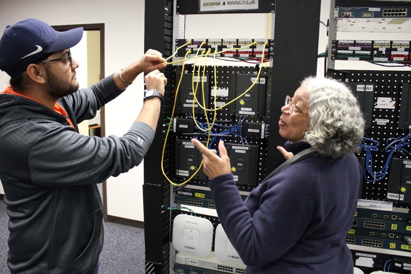 A faculty member helping a student with networking equipment.