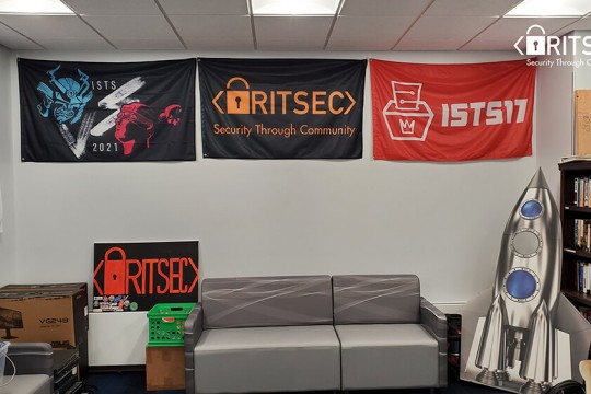 a lounge space with a couch and several banners for the R I T S E C club.