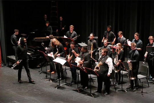 Musical ensemble dressed on state with instruments in hand.