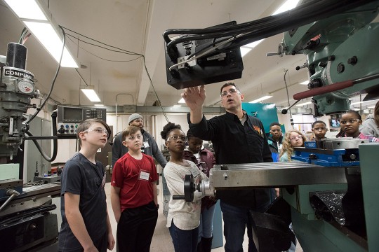 elementary school children watching demo of drill press.