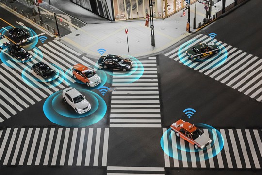 cars at an intersection with WiFi signals above them.