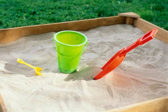 children's sandbox with a pail and two shovels.