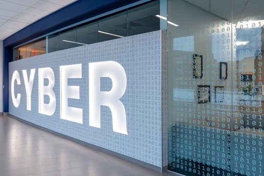 wall with the word CYBER written across it, with rows of zeros and ones, like computer code.