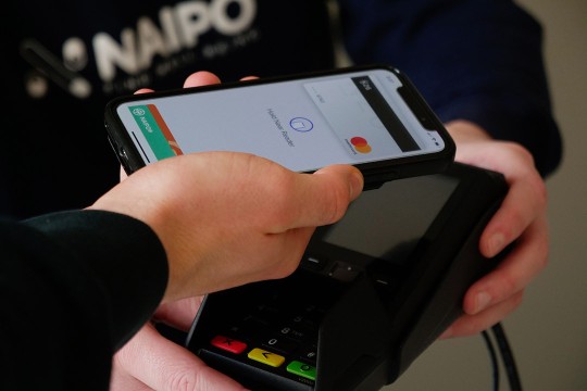 person holding their smartphone over a credit card reader.