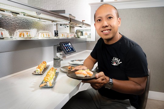 person sitting in a restaurant holding a plate of sushi.