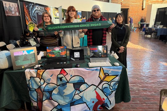 four people stand next to each other at a table themed for 'Mushroom kind's big grass sword'