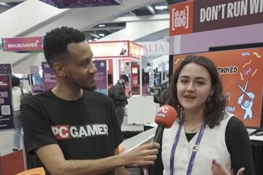 a woman is interviewed by a man in a exposition setting.