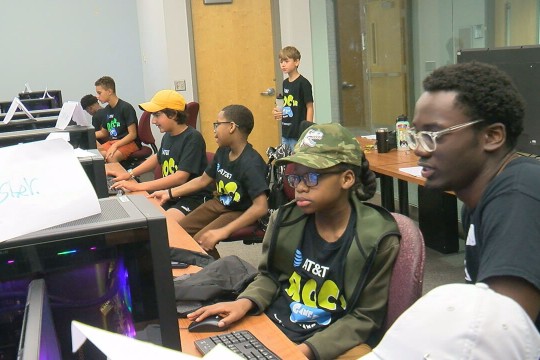 Middle school-aged students work in a computer lab.