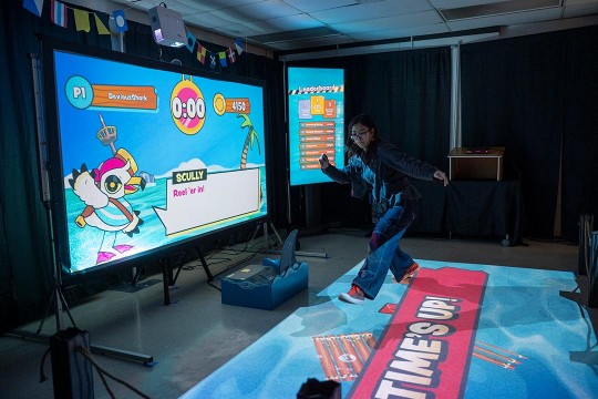 An Imagine RIT visitor jumps while participating in an interactive exhibition called Overboard.