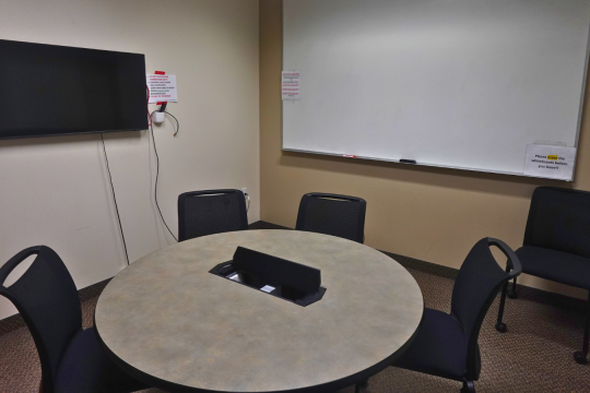 small room with a tv on one wall and white boards on the other walls