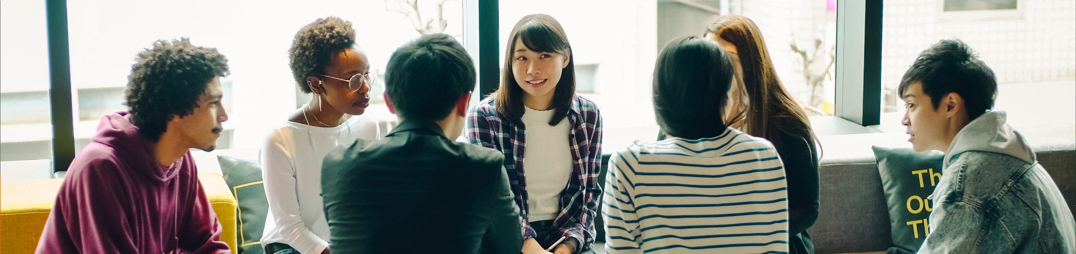 A group of 7 people sitting in a group, talking to each other.