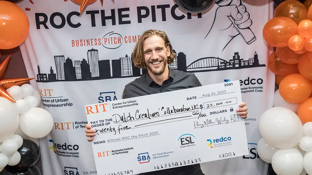 man holding a giant novelty check for 25,000 dollars.