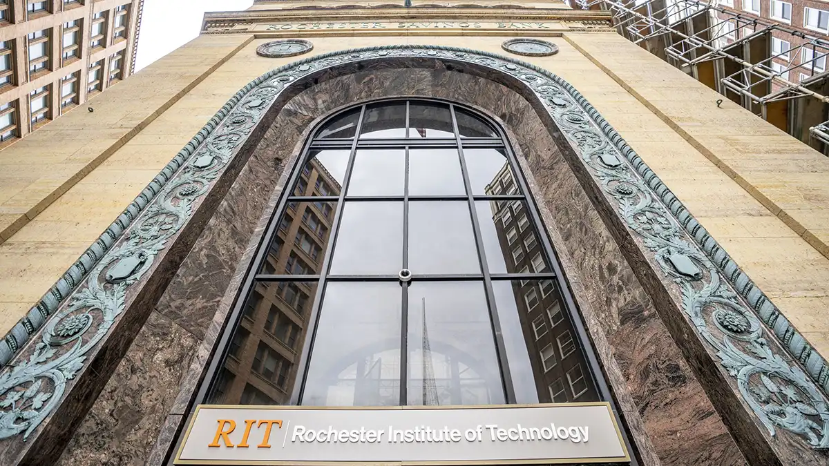view looking up from below of a large old brick building with a large arched glass window in the front.