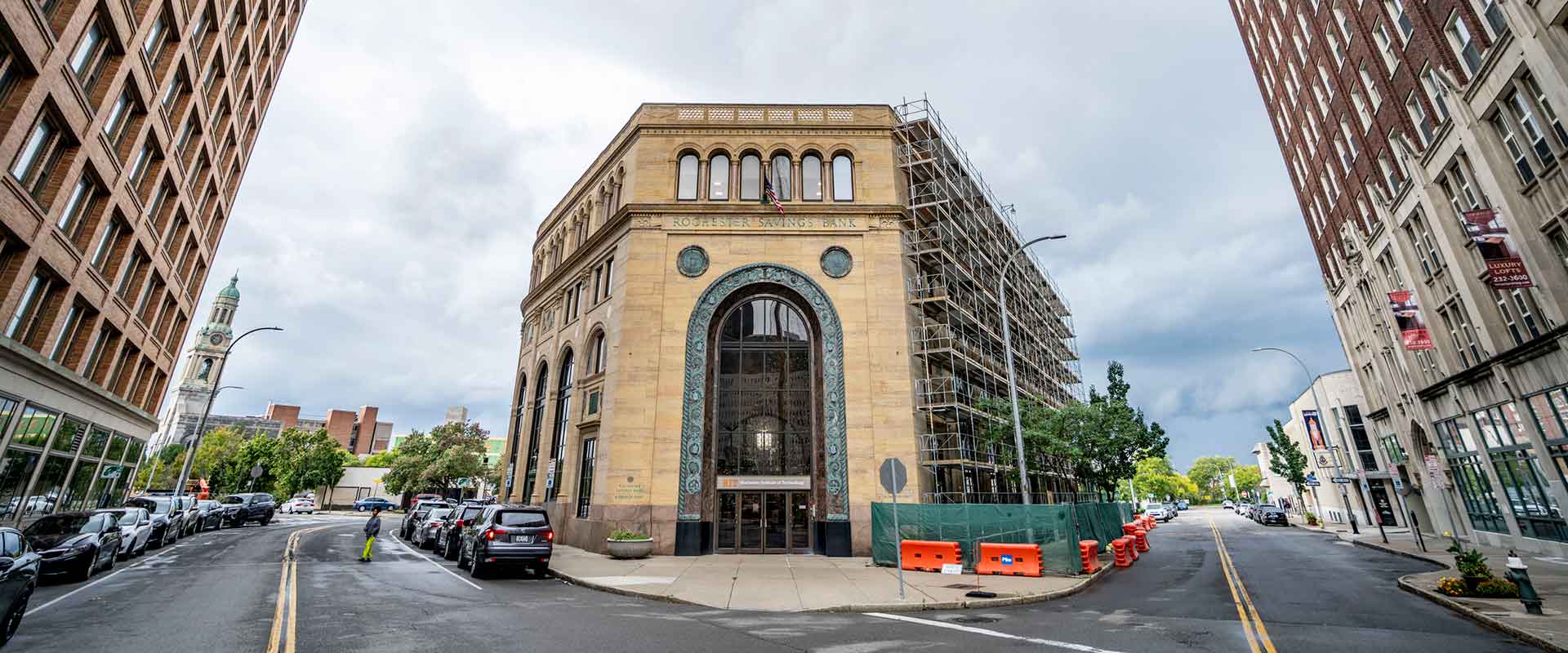 panoramic street view of an older brick building with a large arched entryway.