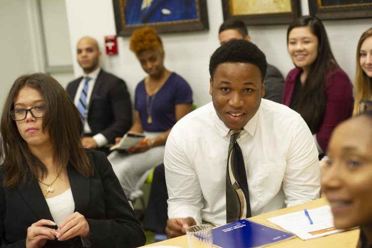 group of people sitting and smiling while listening to a presentation.