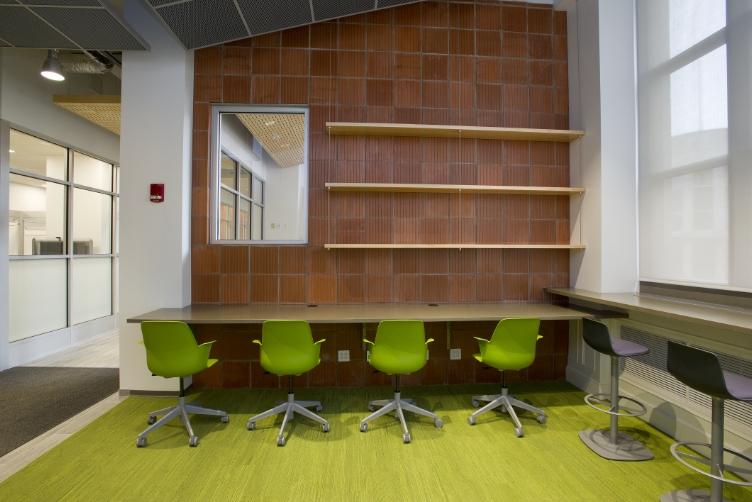 a room with lime green carpet and chairs with a brown tiled wall