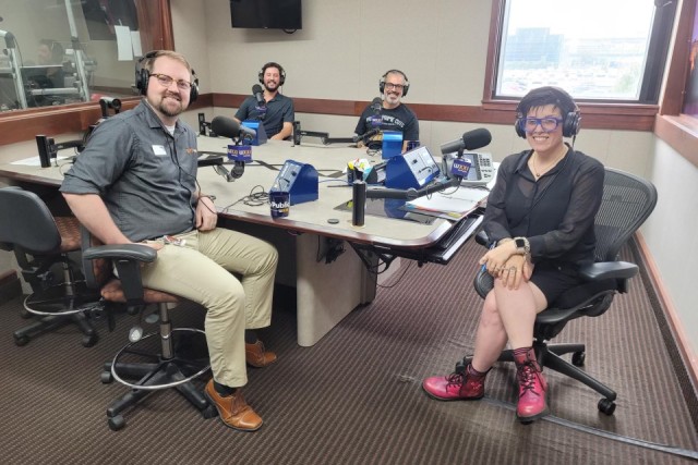 WXXI studios with 4 people at microphones sitting and smiling at camera