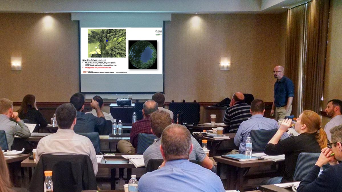 people gathered in a room watching a presentation.