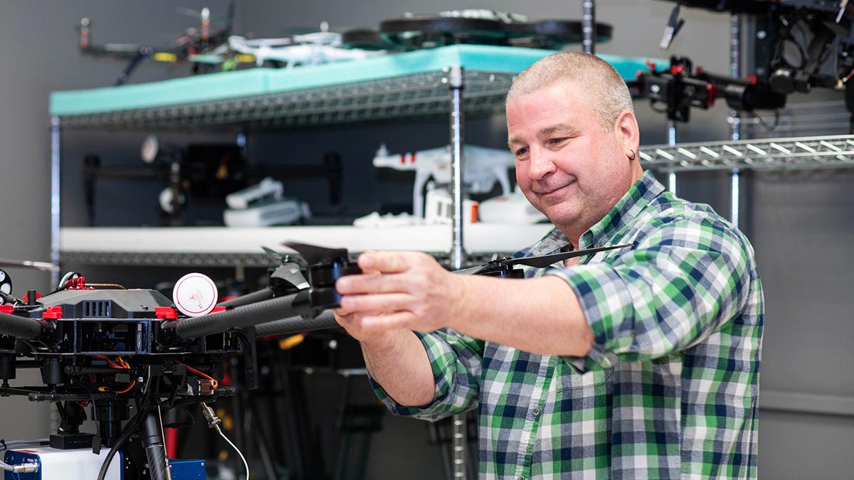 a researcher adjusts a drone in a lab setting.