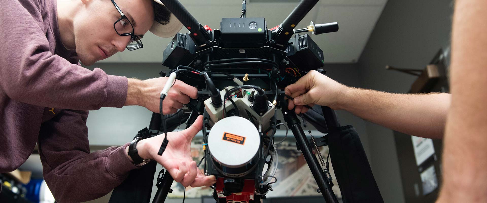 a researcher making adjustments to a drone in a lab.