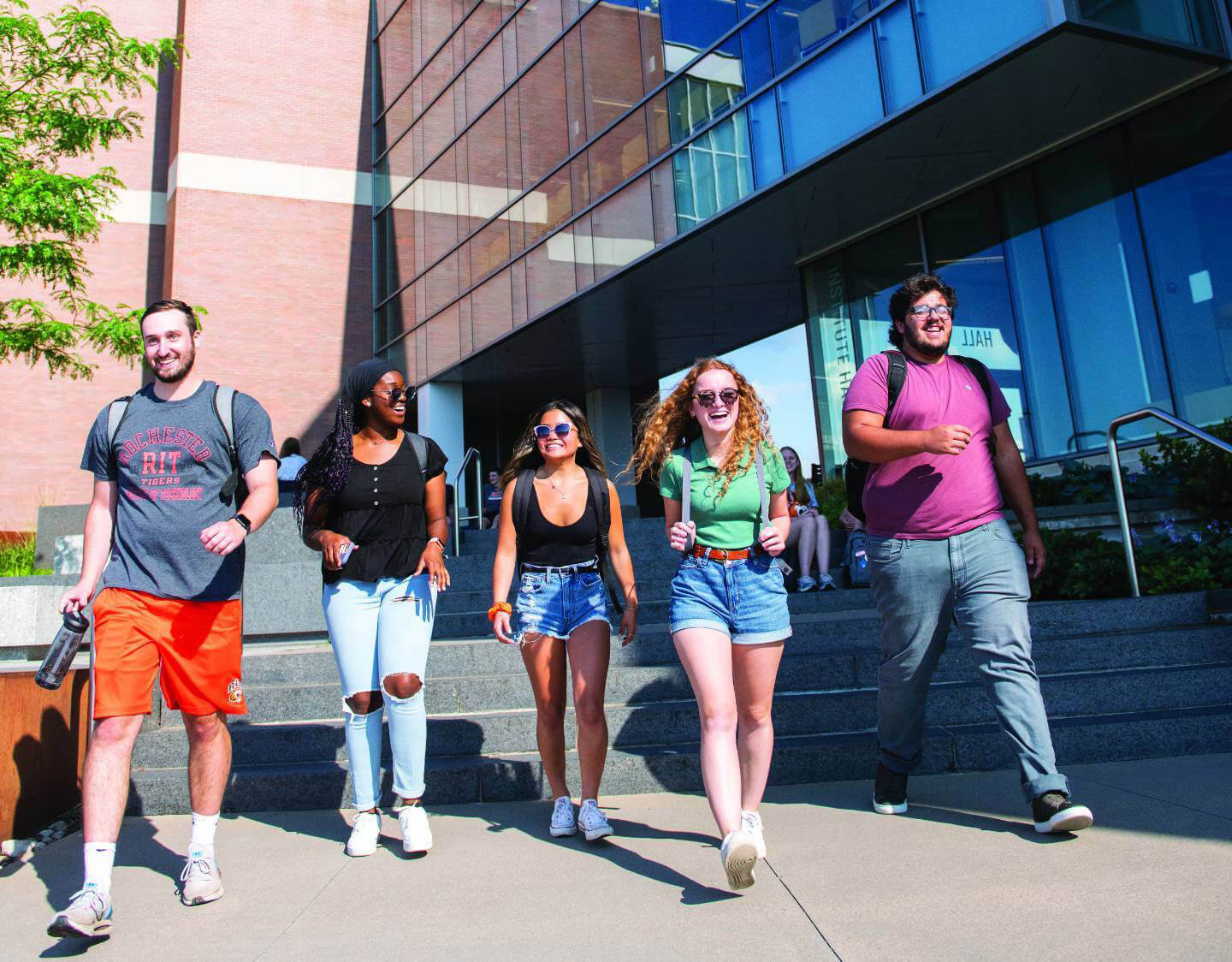 5 students walking through campus on a sunny day