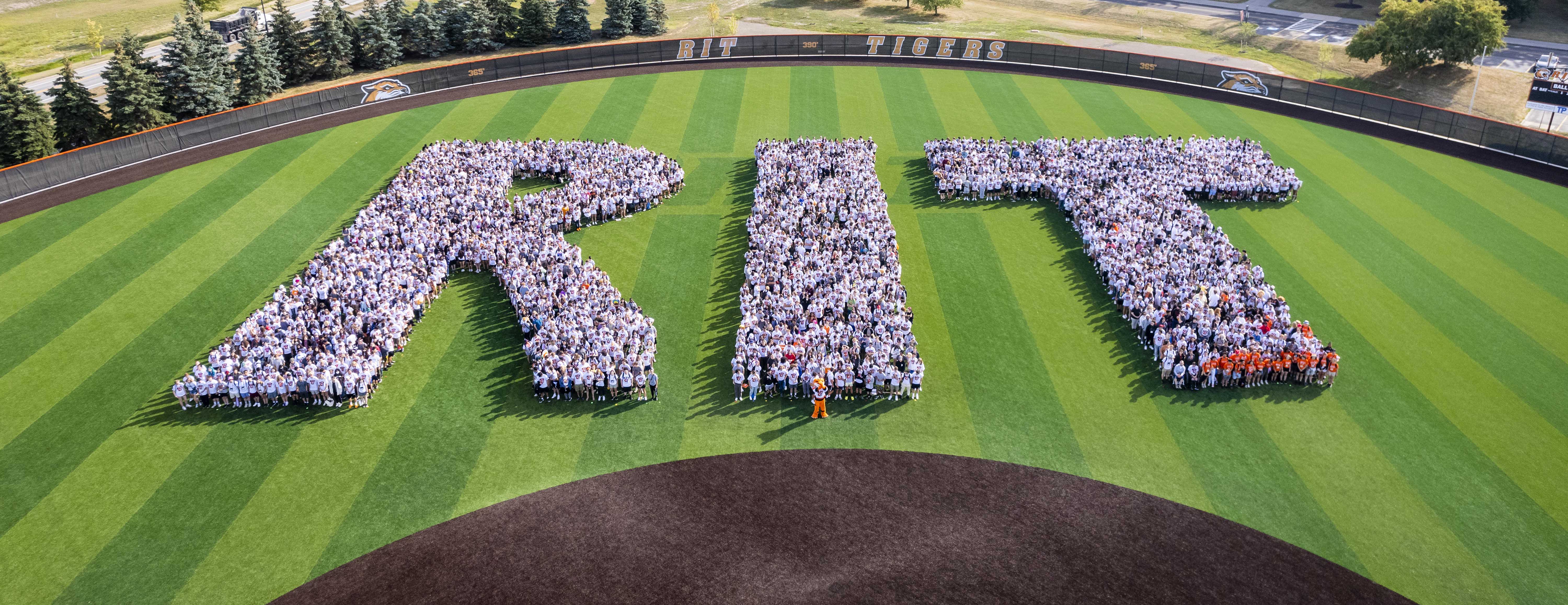 Group photo of RIT Students in the shape of RIT on baseball field