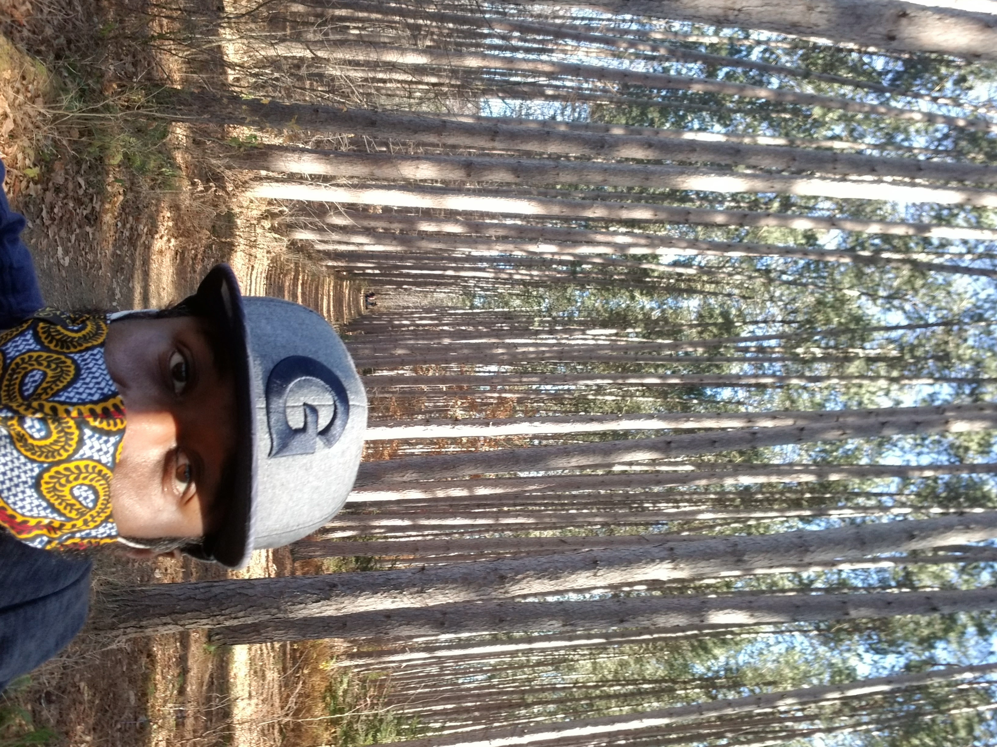 Taj standing on trail surrounded by trees