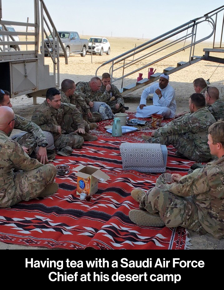 men sitting on blanket drinking tea in desert