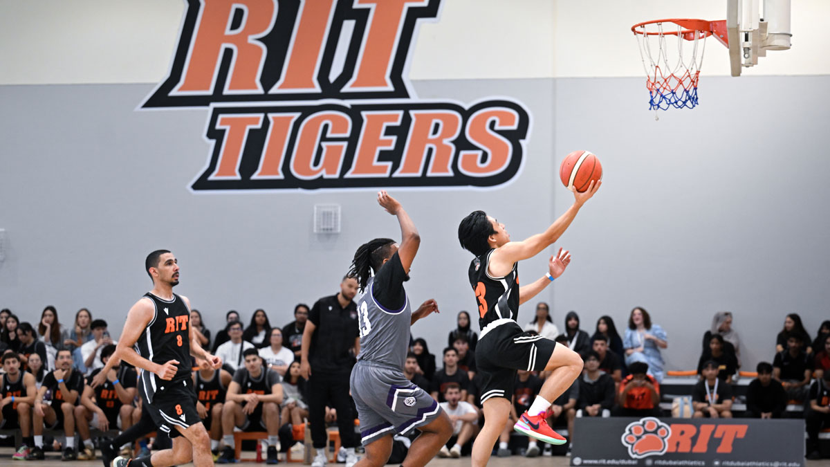 RIT Athlete putting basketball in the basket