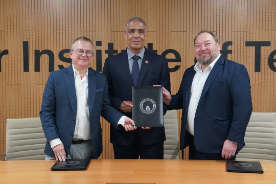 three men stand behind a table holding a partnership agreement.