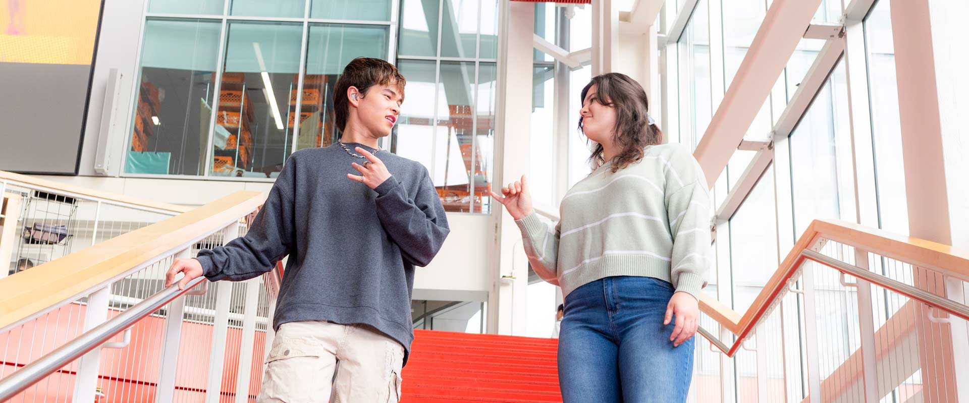 two students walking down a stairway communicating in American Sign Language.