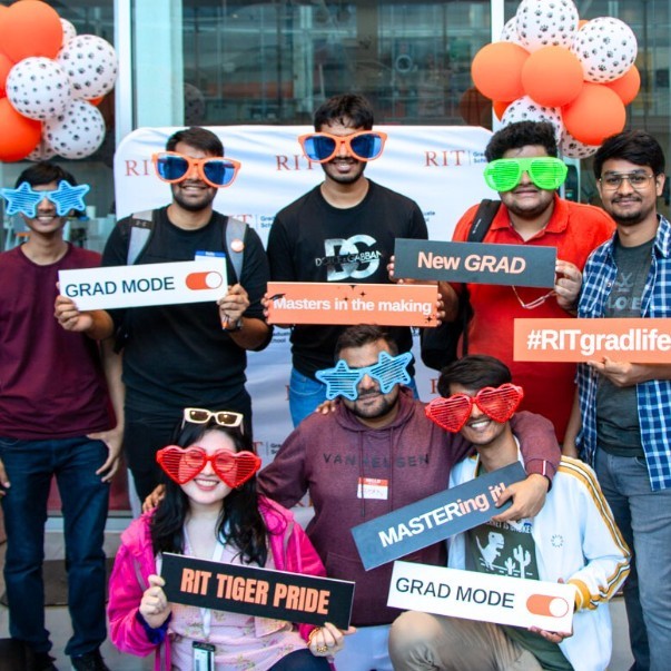 Students pose at step and repeat with silly props for semester kickoff event