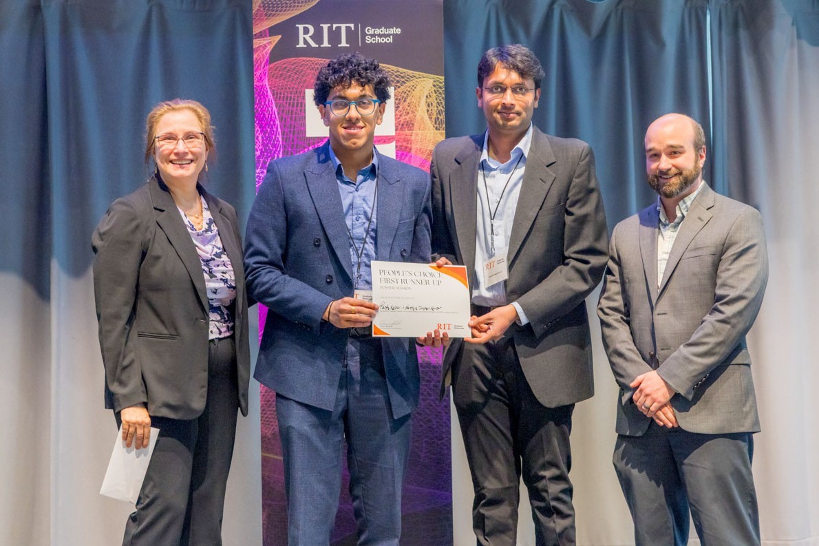 student poses at center stage with 3 faculty and a certificate during the graduate showcase