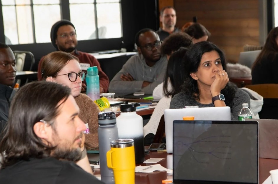 group of students at round tables listen to presenter at writing retreat