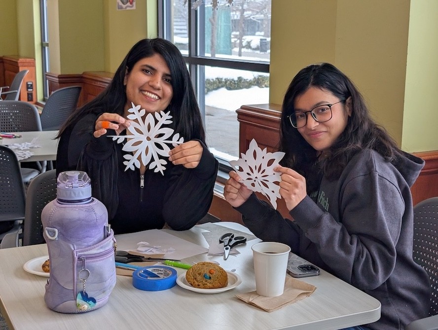 RIT graduate students seated around a table, enjoying coffee and conversation during a Graduate School Coffee Hour.