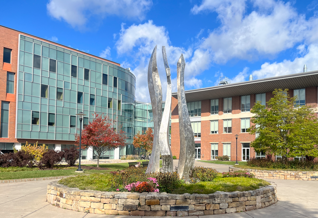 RIT’s Unity sculpture against a vibrant autumn sky Created by RIT faculty artists Juan Carlos Caballero-Perez and Leonard Urso, the sculpture
