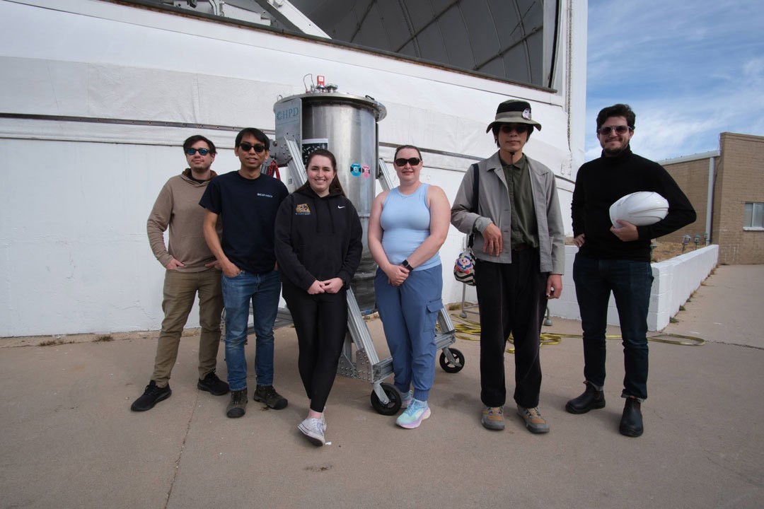 A diverse group of five adults smile for a photo in a meeting room suggesting collaboration.