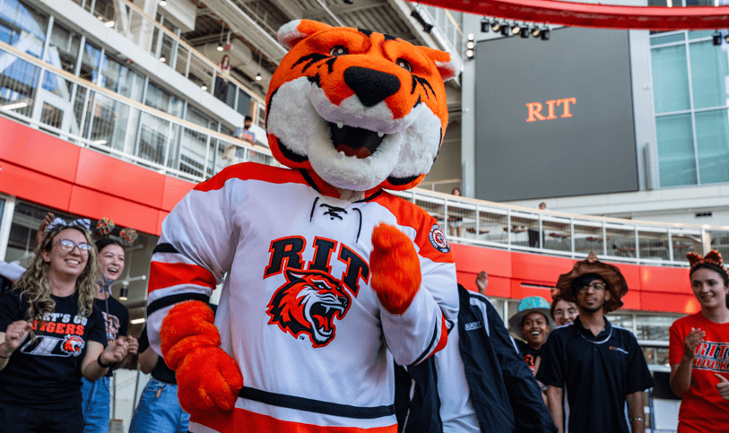 RIT mascott with students grouped around them in the SHED atrium
