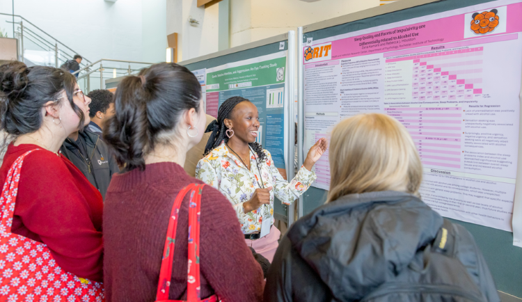 An RIT Grad student presenting their poster at the Graduate Showcase 2025 to the attendees