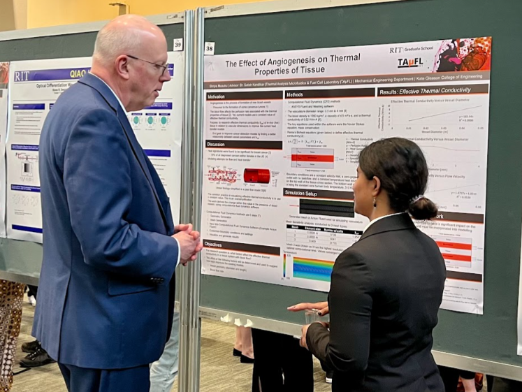 Dr. Munson listens to student present their poster in fireside lounge at grad showcase