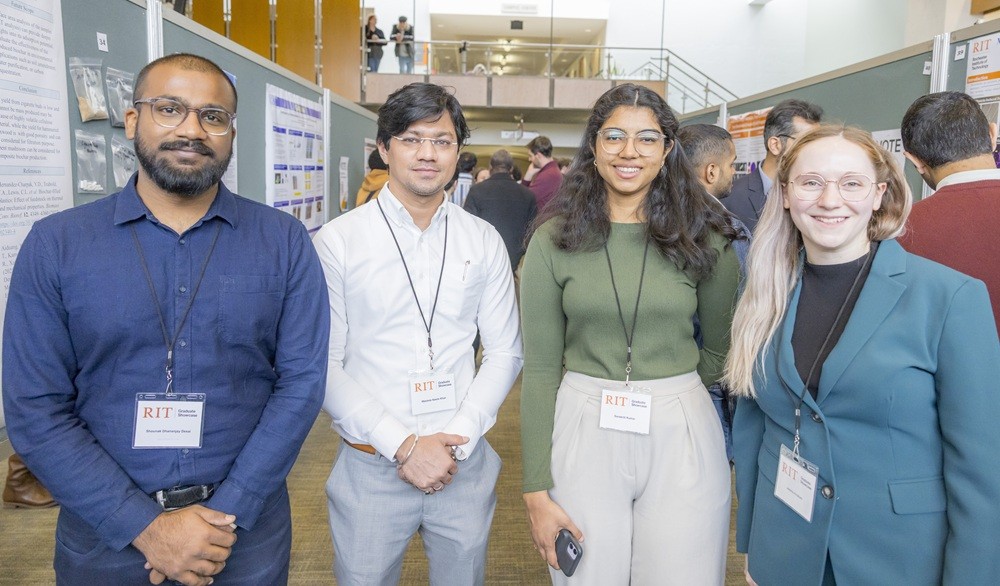 4 students pose at their posters during the 2025 graduate showcase in the SAU building