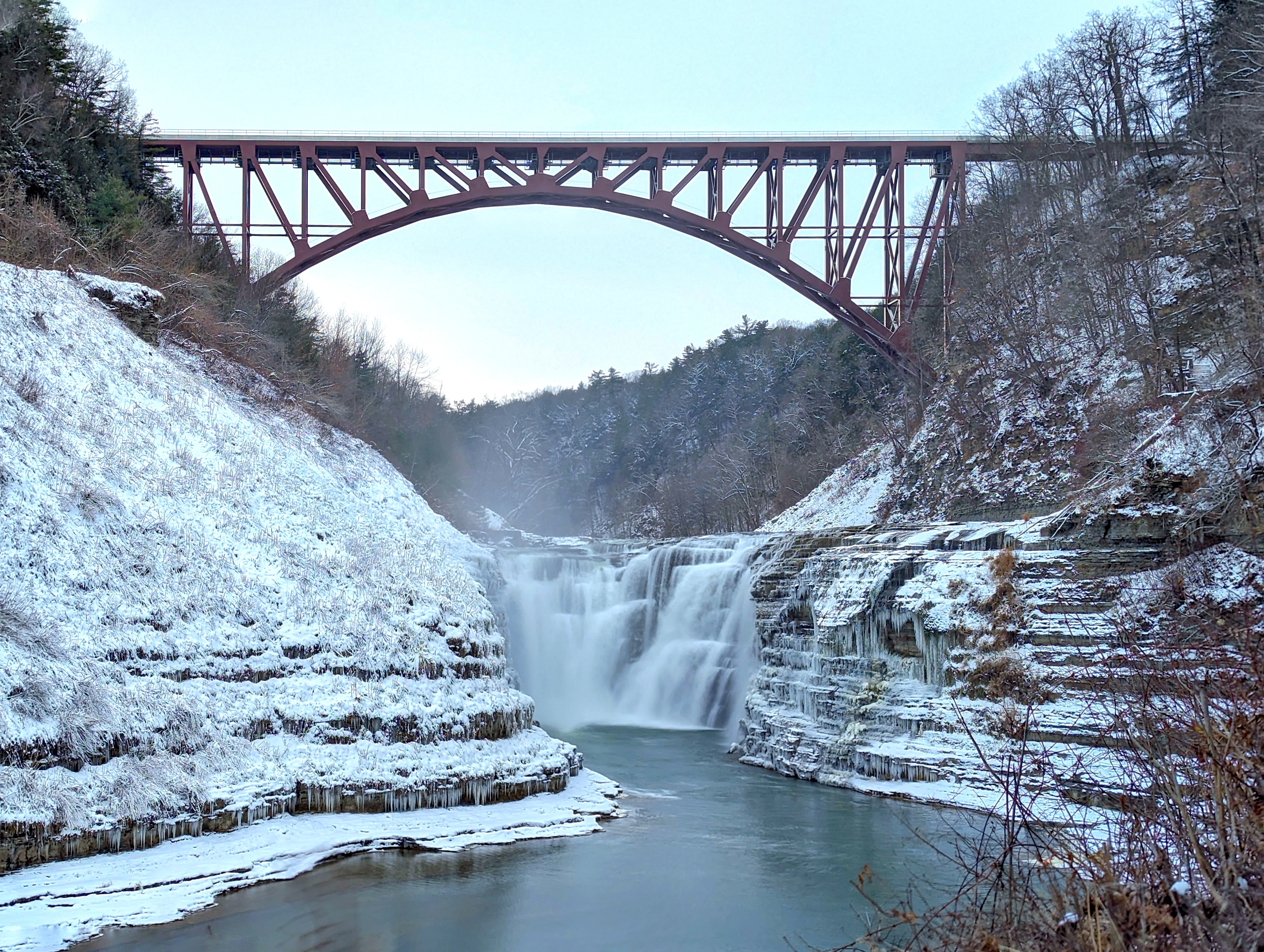 New graduate students sitting on a circular table with one student holding up and showing a gray RIT T-shirt while others smile at the camera