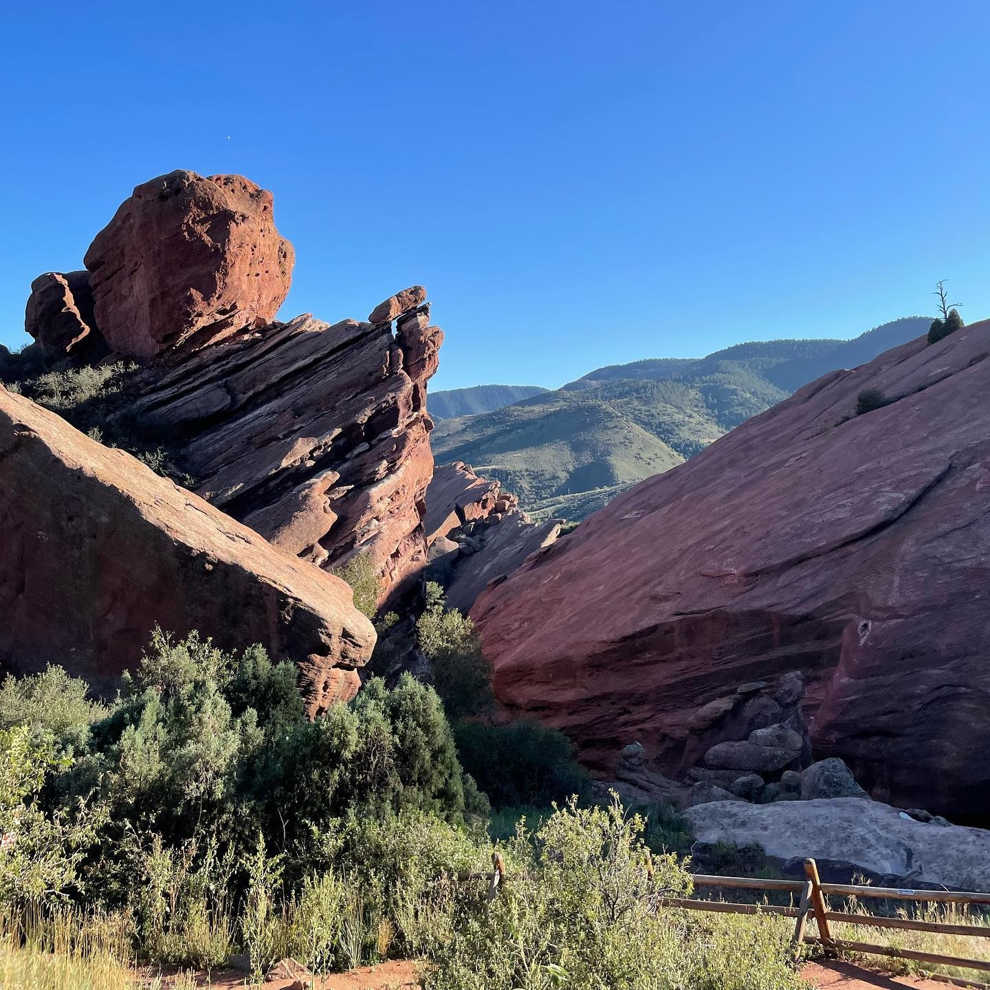 New graduate students sitting on a circular table with one student holding up and showing a gray RIT T-shirt while others smile at the camera