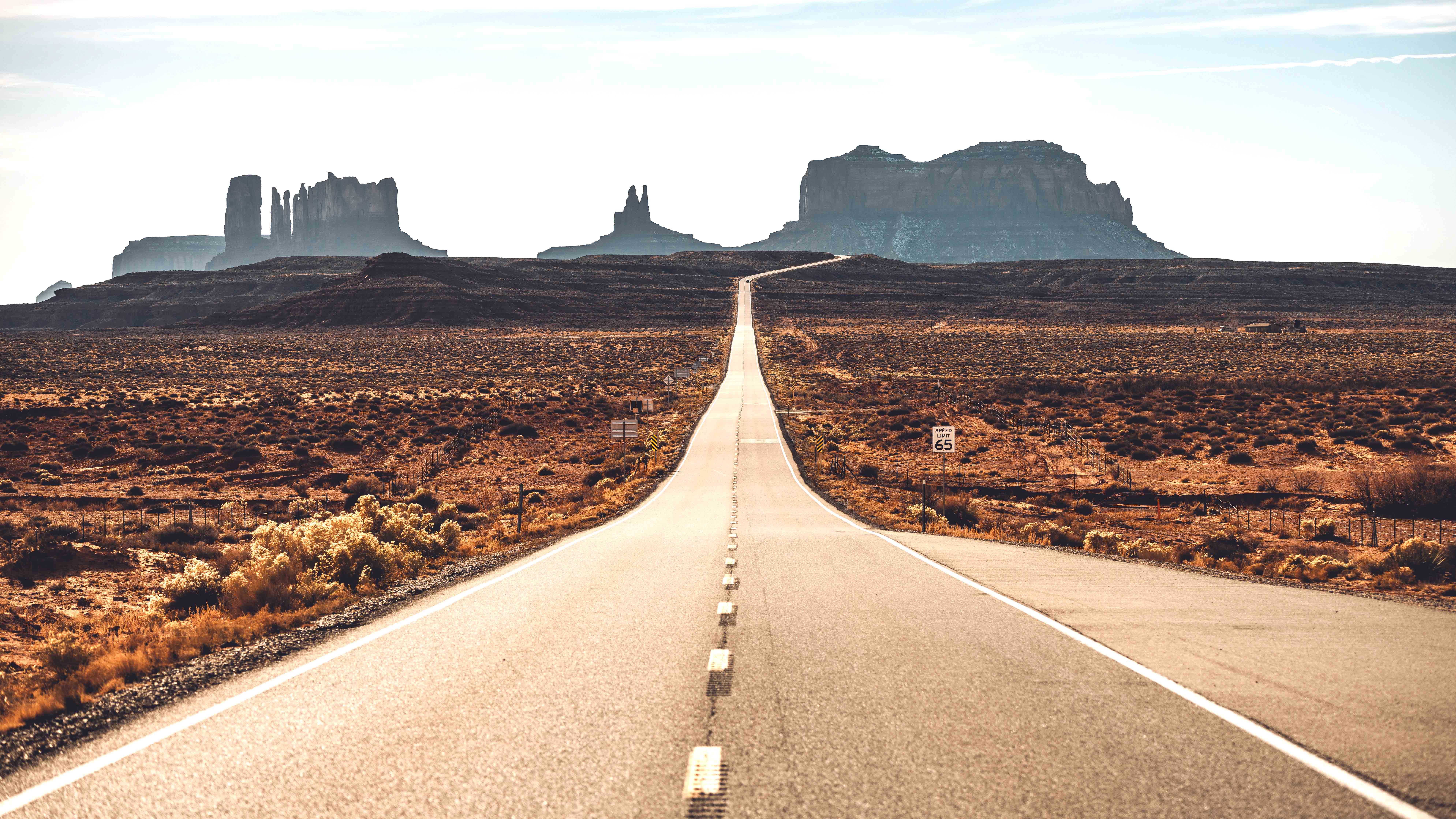 New graduate students sitting on a circular table with one student holding up and showing a gray RIT T-shirt while others smile at the camera